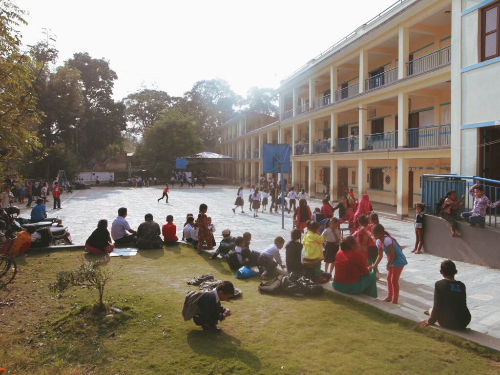 A lively scene of children playing and socializing in a sunny school courtyard, creating a vibrant atmosphere.